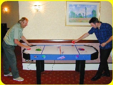 Two players with a mallet each to strike the puck into the opponents goal