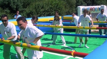 Inflatable version of popular table game placing players right in middle of it.